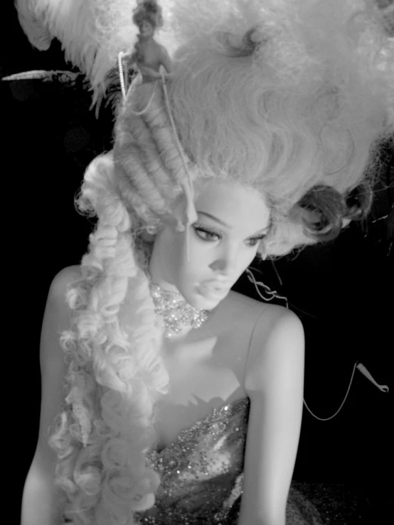 a woman in black and white holding a dress with large feathers