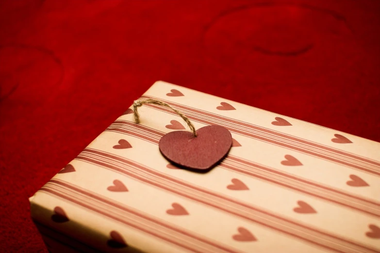 a small red heart hanging on a package of gift