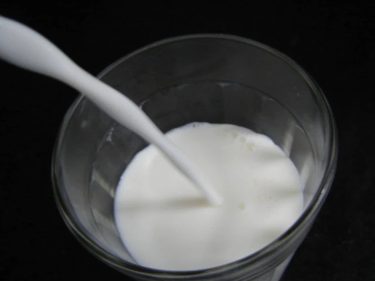 the milk is in the cup with a plastic spoon