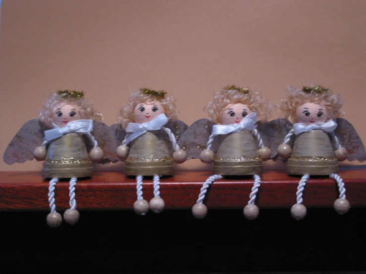 three tiny angel bells hanging from the top of a wooden table