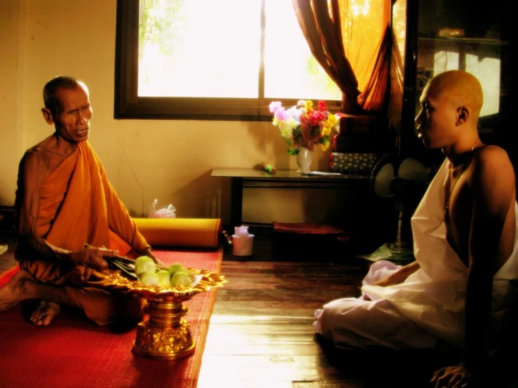 there is a monk sitting in front of a young man