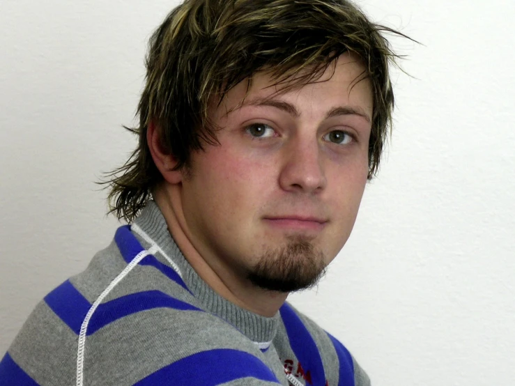 a man with the frizzy brown hair wearing a striped sweater