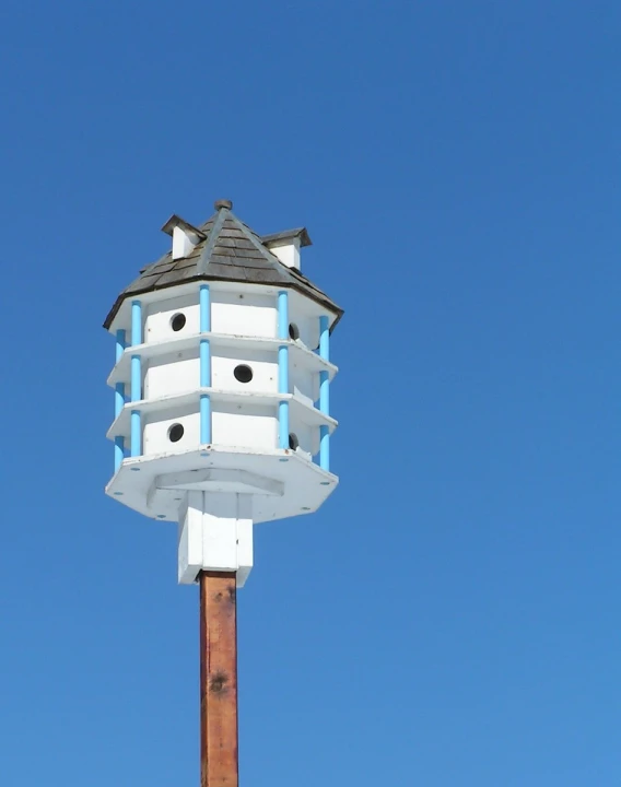 a tall white bird house with two windows