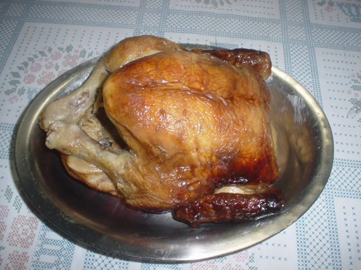 roasted turkey in a silver dish with a floral tablecloth