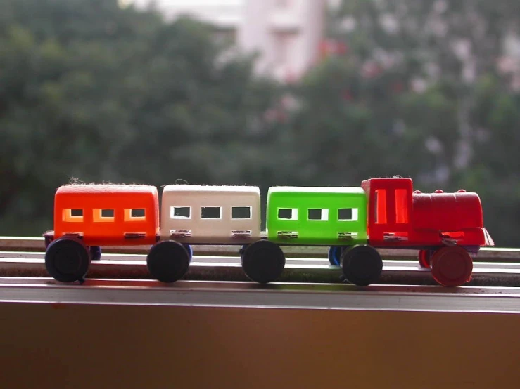 small colorful toy cars are lined up on a window sill