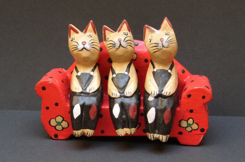 a red and black toy couch with three kittens sitting on it
