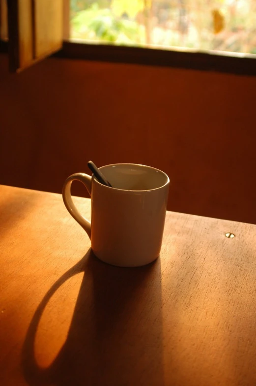 a mug on a table next to a window