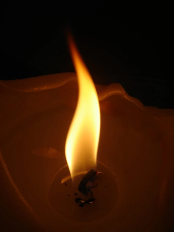 a lit candle in the middle of a black background