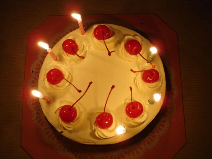 white cake with lots of cherries on top surrounded by lights