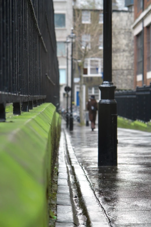 an empty city street with lots of rain and a person walking