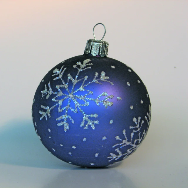 a blue glass ornament has snowflakes all over it