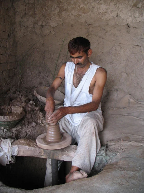 man making pottery by spinning in the process