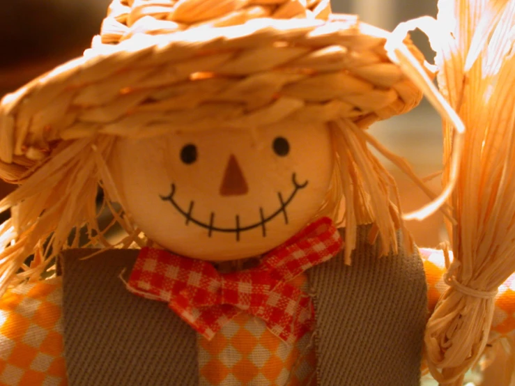 an orange scarecrow doll with a straw hat and bow tie