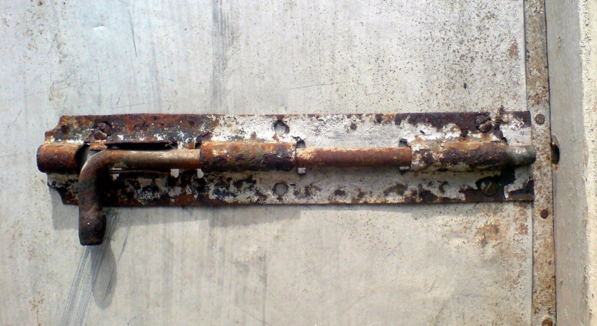 an old rusted, rusty metal latch on an abandoned door