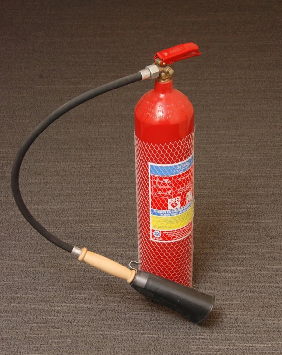 red fire extinguisher next to an open hose on a floor