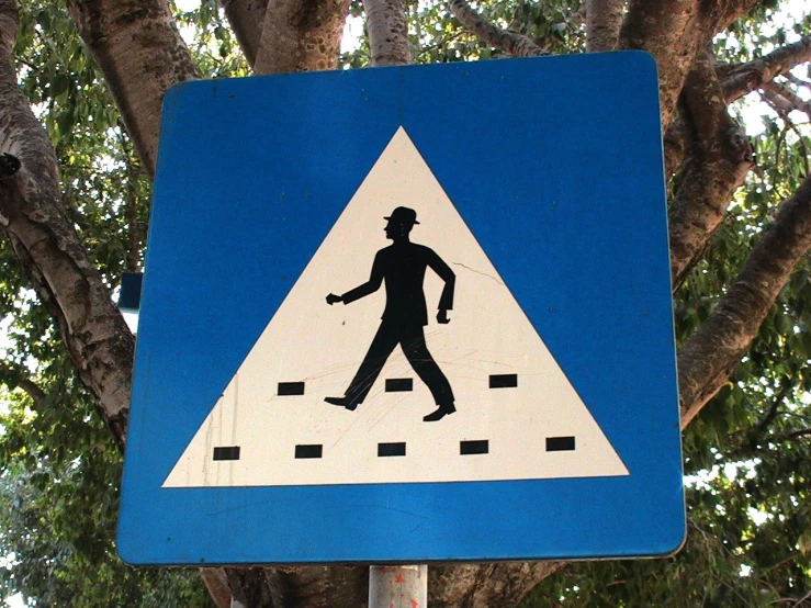 the pedestrian sign is in front of some trees