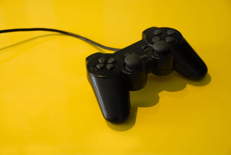 two black video game controllers on a yellow table