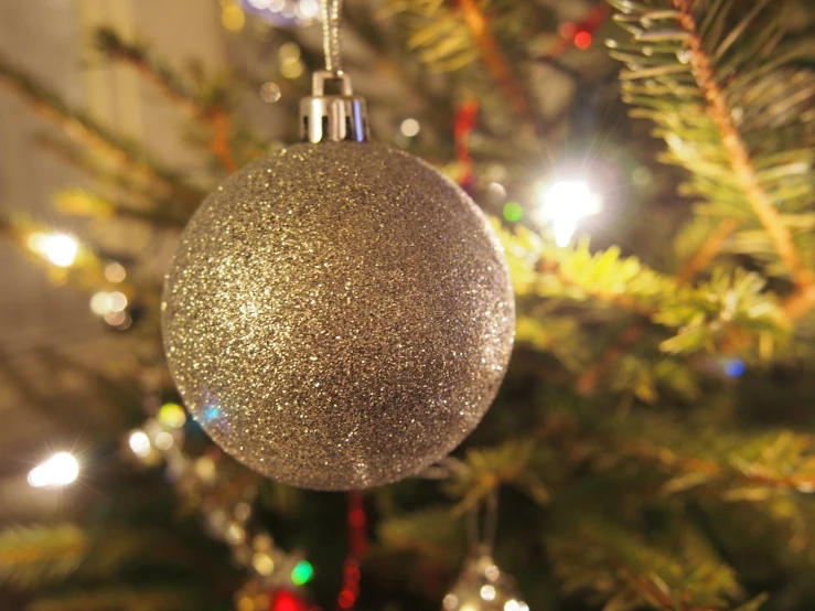 a close up of a silver ornament hanging on a christmas tree