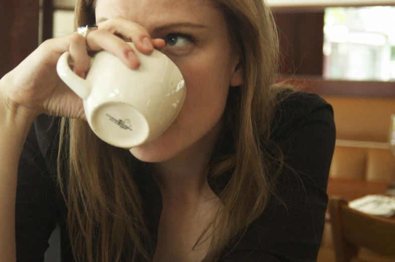 a beautiful blond woman holding up a white cup