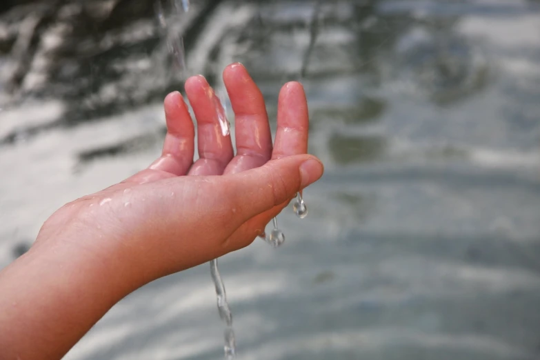 a hand holding a water faucet coming out from a river