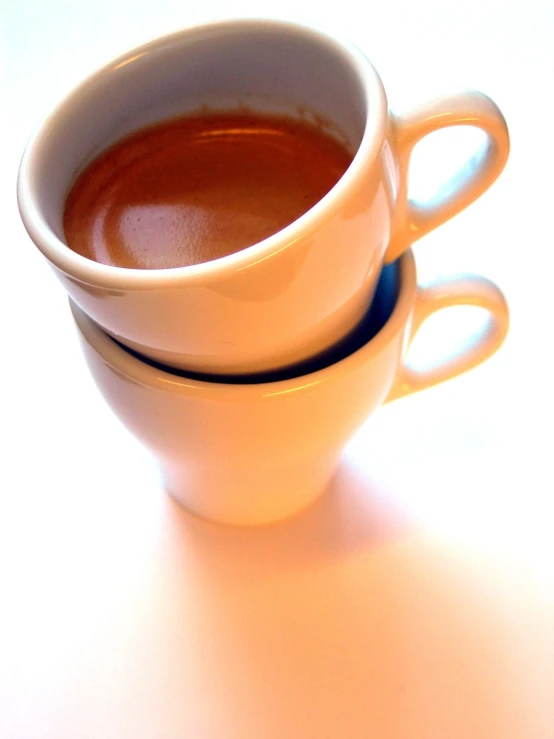 two cups filled with  coffee on a white table