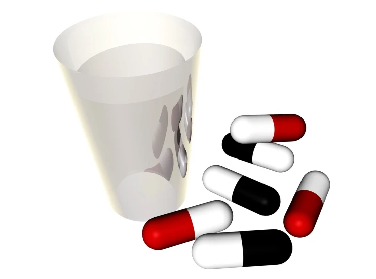 pills are placed beside a plastic cup on the ground