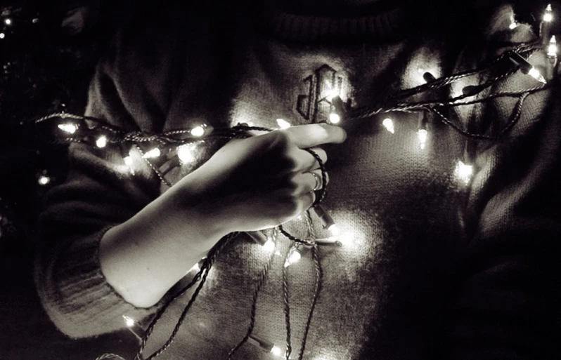 a person wearing a sweater holding a string of light