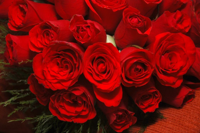 a bunch of red roses sit on top of a table