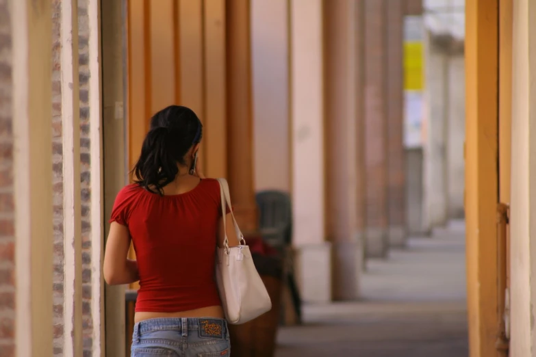 a woman wearing a red shirt and carrying a bag