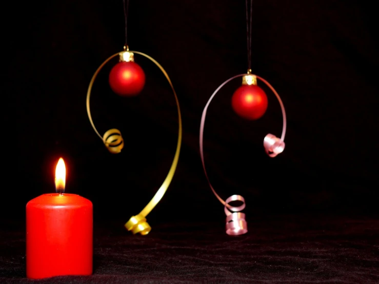 two christmas ornaments next to a lit candle