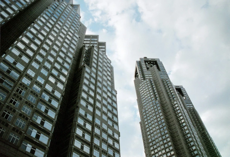 looking up at tall buildings against a cloudy blue sky