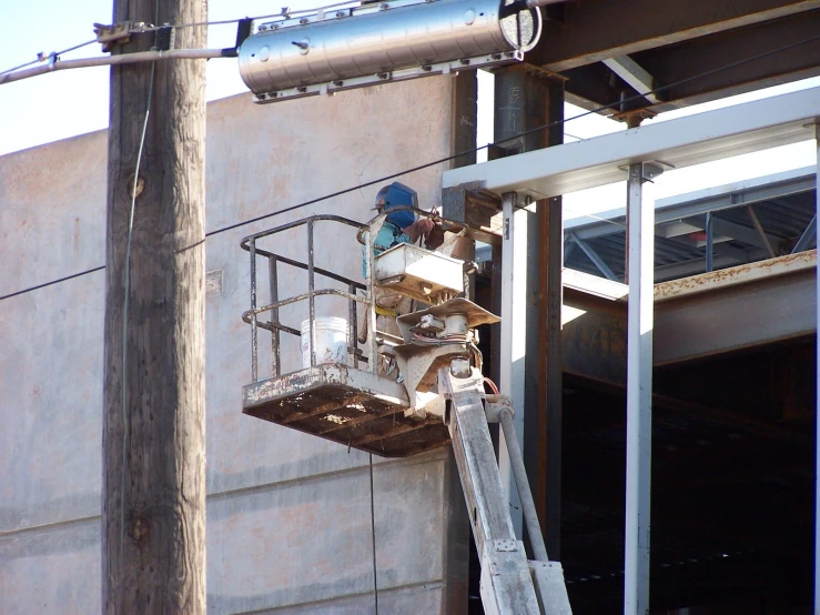 man on a cherry picker removing a piece of construction