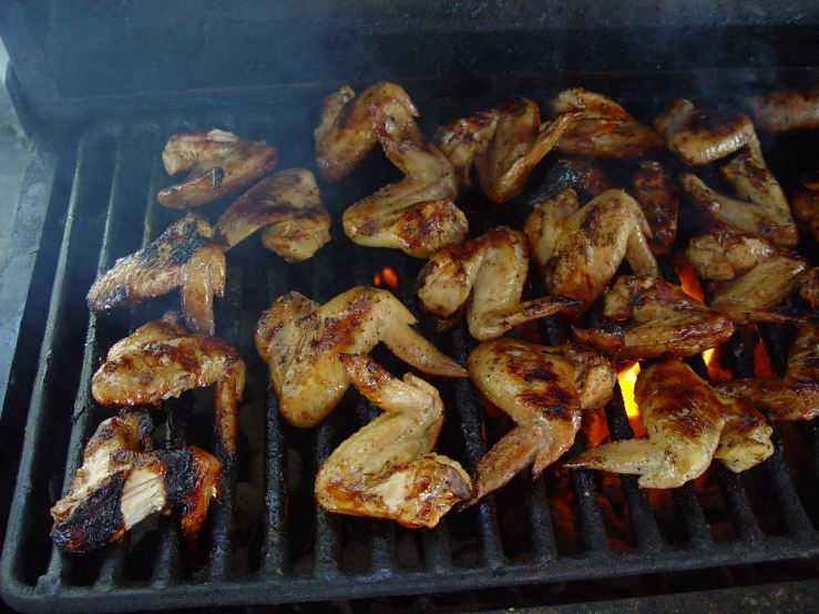 a grill with lots of chicken and flames on it