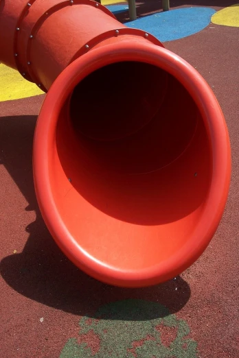 a large orange pipe in a playground near the play area