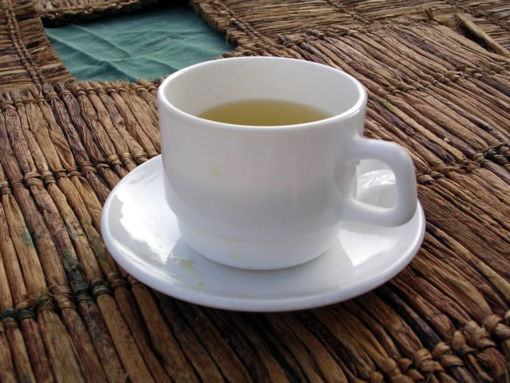 a white cup and saucer on a woven mat