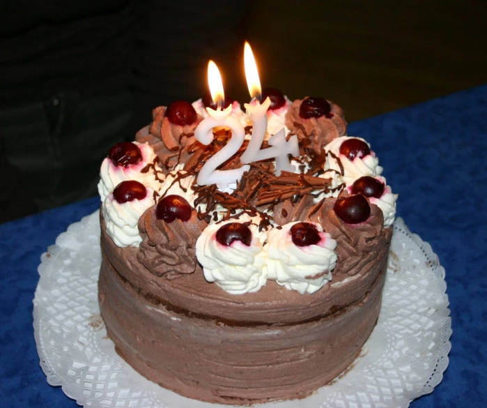 the birthday cake is decorated with cherries, chocolate frosting and two candles