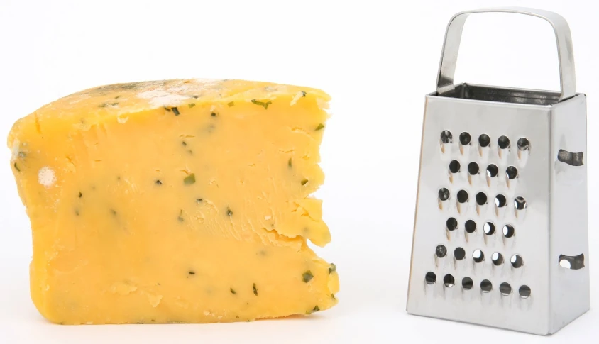 a piece of cheese is next to a grater