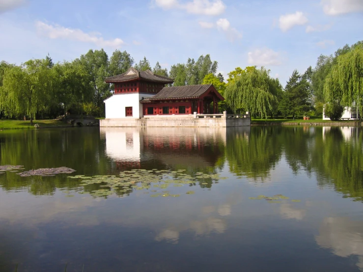 the building is by the water that is reflecting the trees