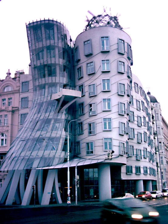 a car passing by an unusual building near the street