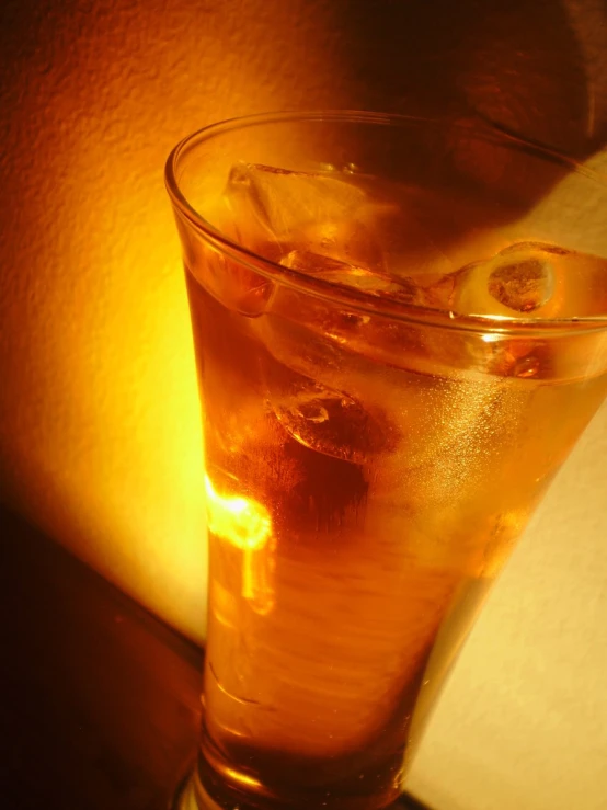 a drink with ice and yellow liquid is sitting on a table