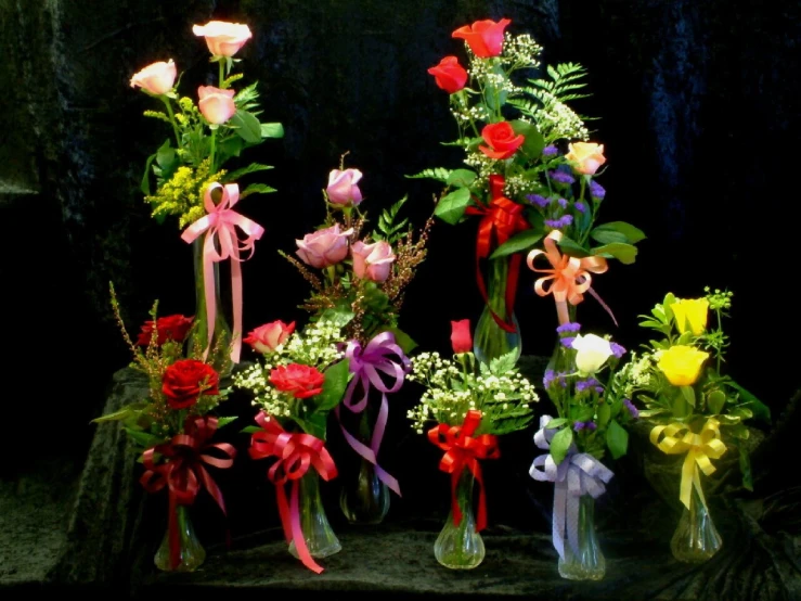 several vases with flowers and ribbons attached to them