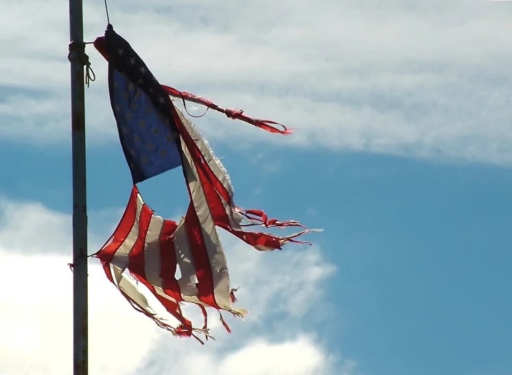 two american flags are flying against the sky