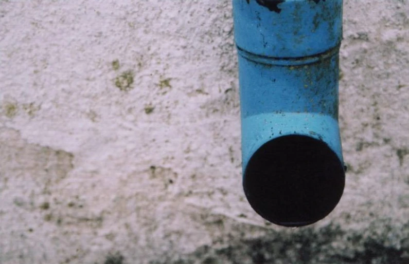 a blue pipe attached to a gray wall