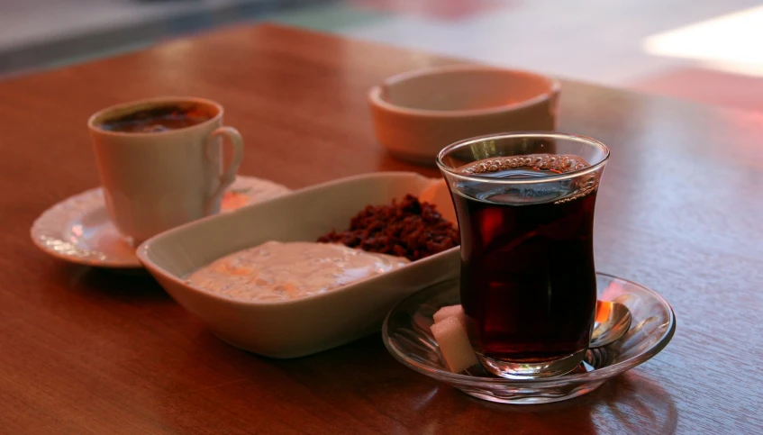 a glass of tea, some spices and a bowl of food on a table