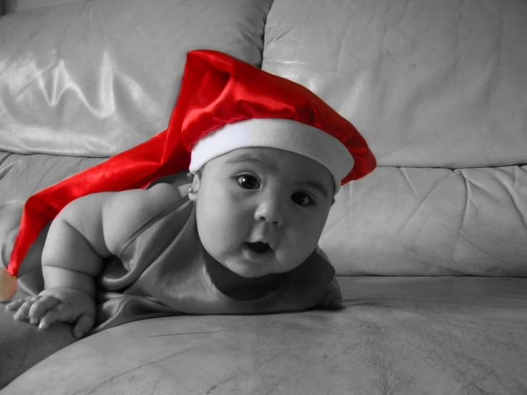 a baby wearing a santa hat lying on a pillow