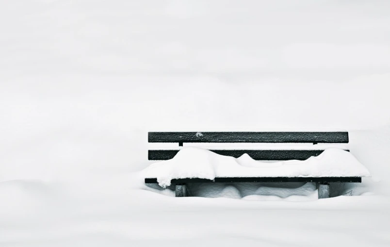 a bench sitting in the snow outside during a winter storm