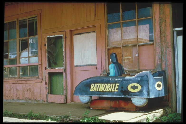 old painted blue vintage batmobile in front of a building