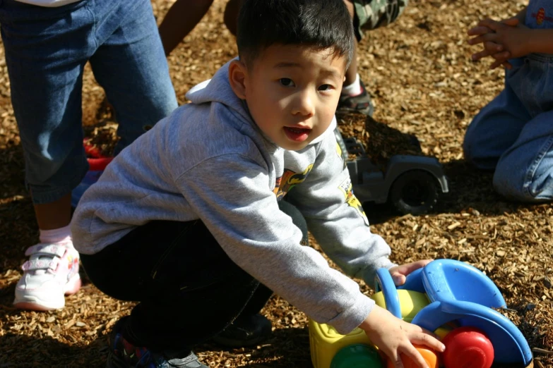 small child playing with toy truck with adults nearby