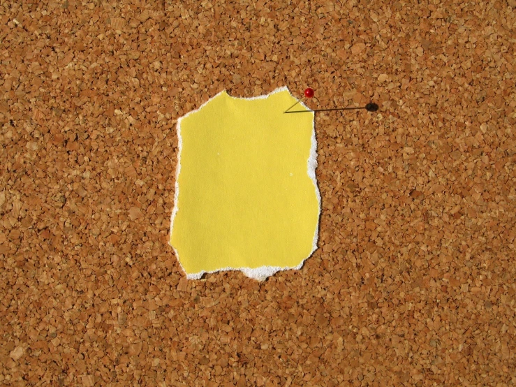 a piece of yellow paper pinned to the side of cork
