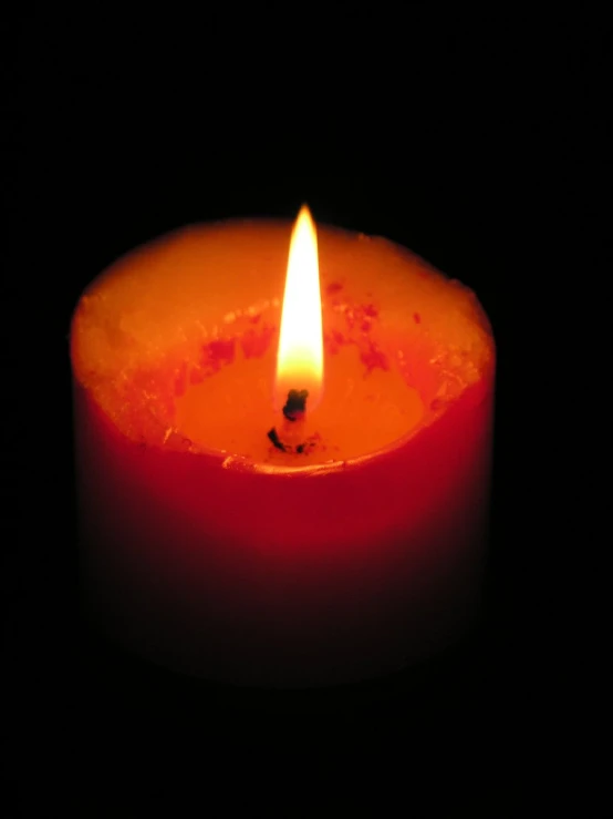 a close up of a red candle on a black background